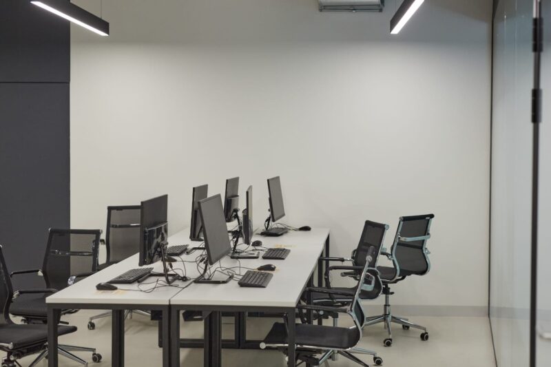 An office with a massive black desk, chairs, and computers.