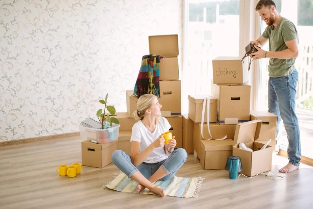 A couple is standing in a room full of packed boxes.