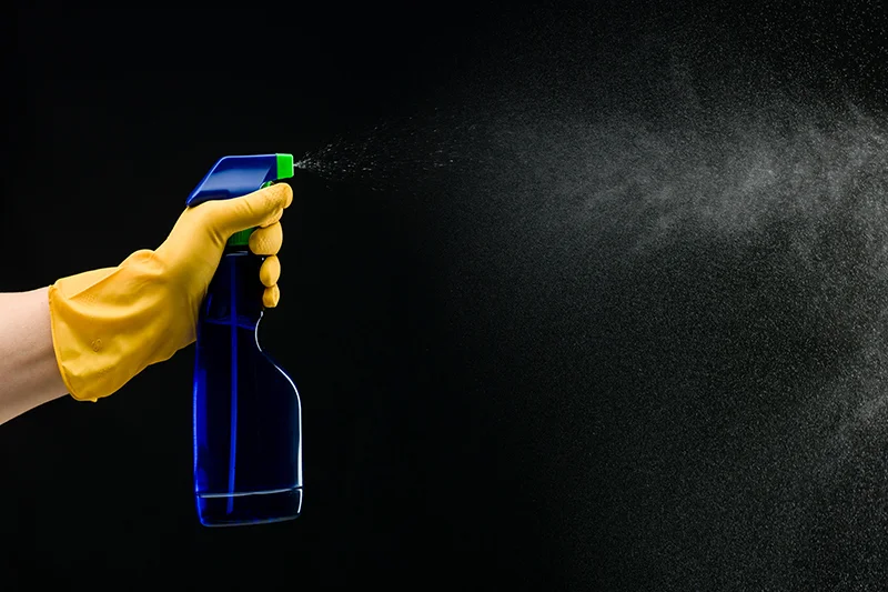 A hand holding a blue spray bottle.