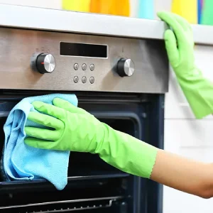 A maid is cleaning a stove.