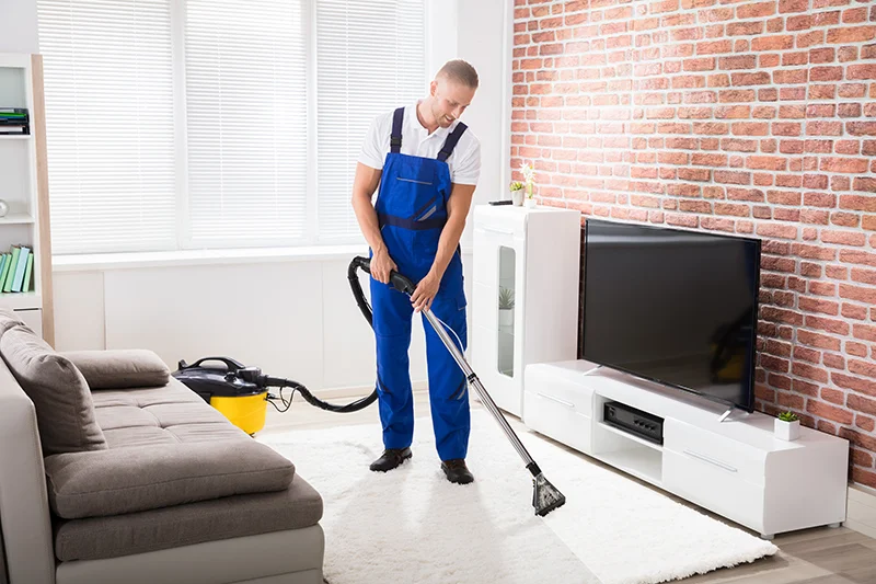 A maid is vacuuming a living room carpet.